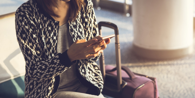 Women sitting with her luggage and working on mobile